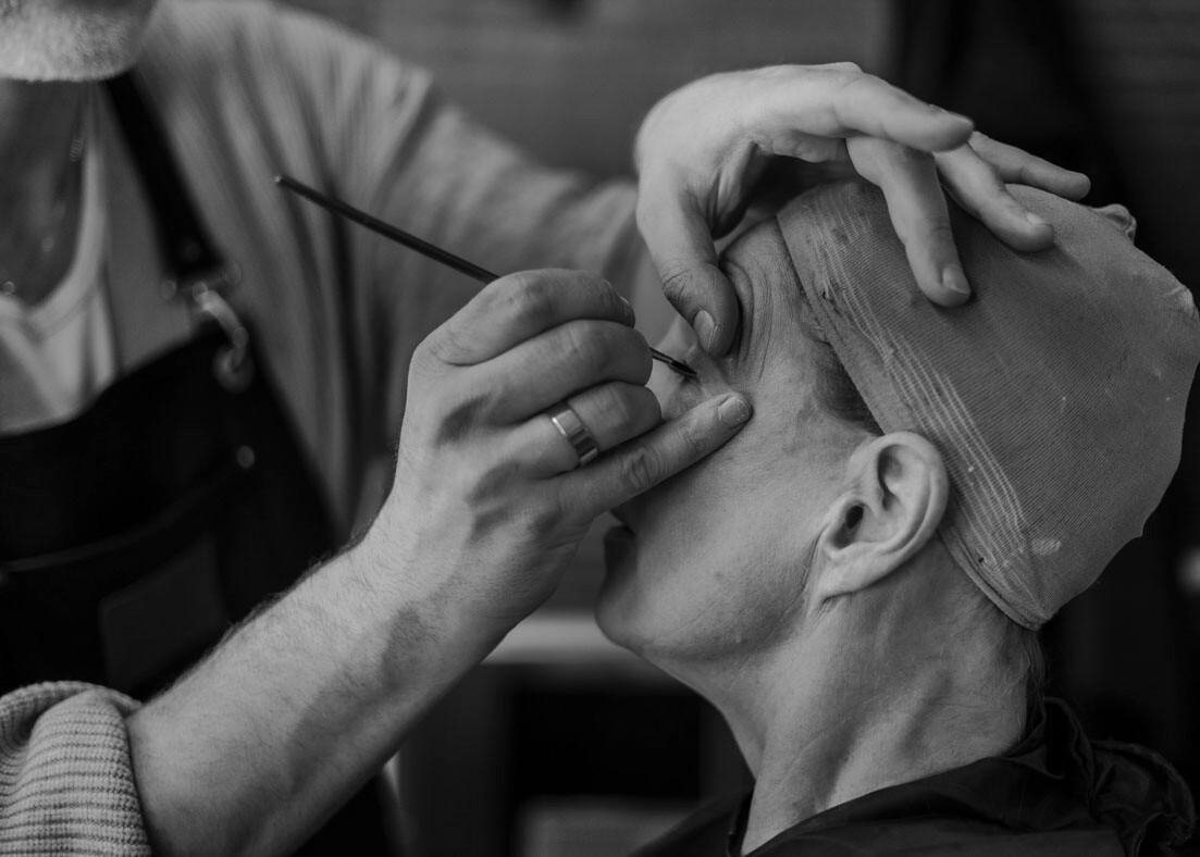 Make-up-Artist schminkt Schauspieler für die Aufführung von Gefährliche Liebschaften